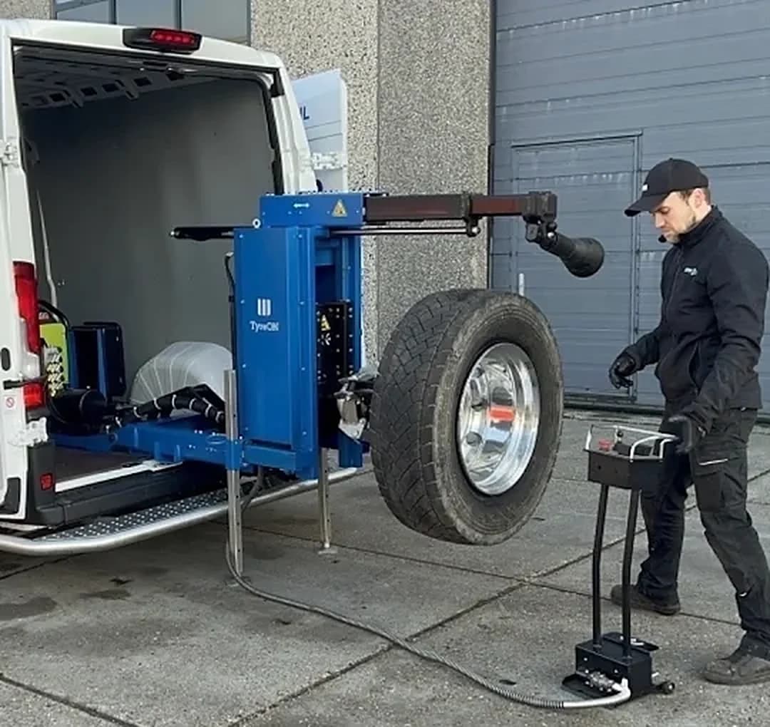 Monteur zet een truckwiel met een bandenlichter naast de servicebus